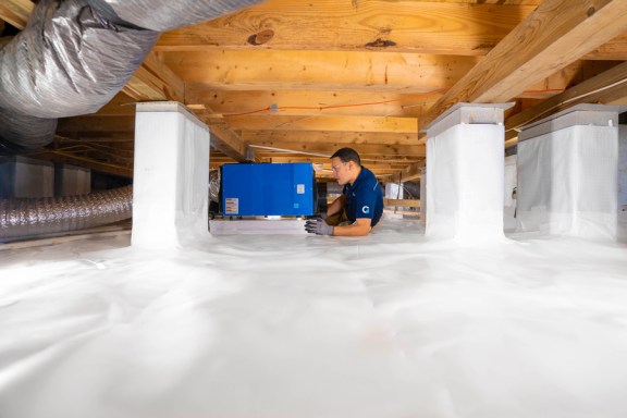 groundworks installer in encapsulated crawl space next to dehumidifier