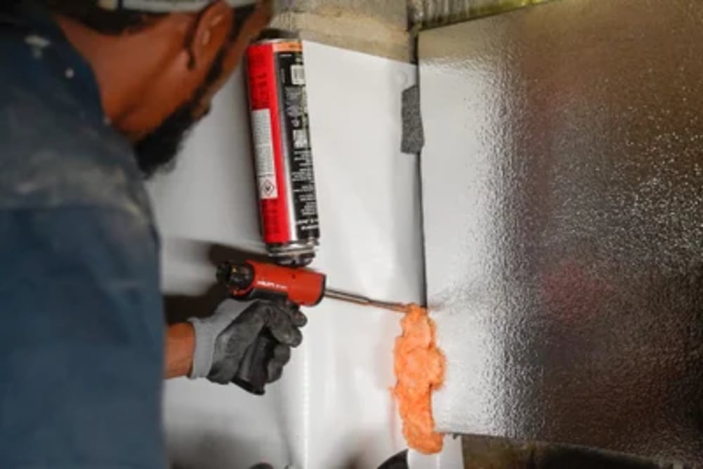 Groundworks man filling in gap in crawl space with insulation