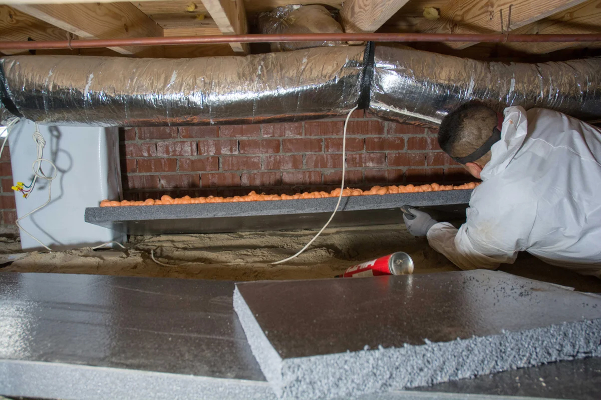 Groundworks tech working in crawl space fixing insulation