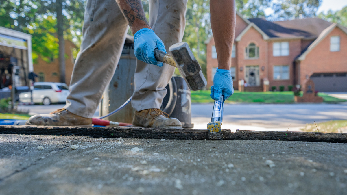 Crew hammering driveway in front of brick house