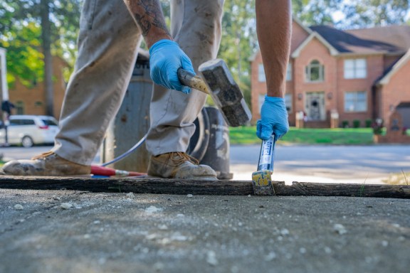 Crew hammering driveway in front of brick house