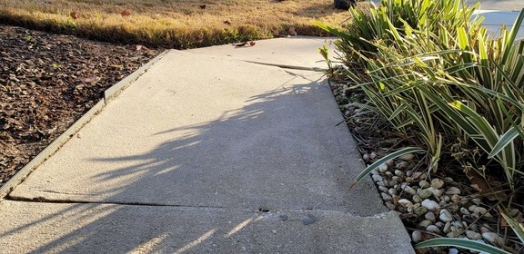 An uneven sidewalk on the exterior of a home.