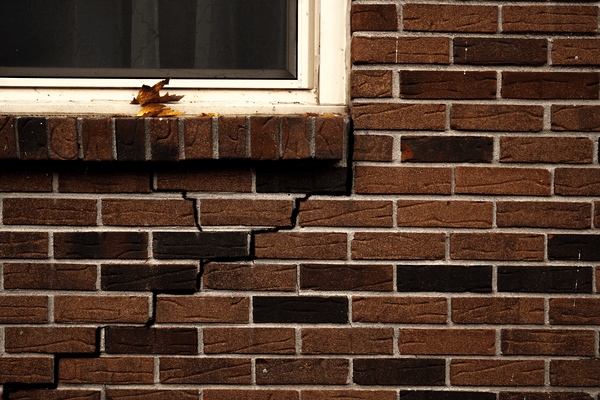 Cracked exterior brick wall under window.