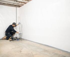 a man extending sump pump discharge pipe line in corner of basement