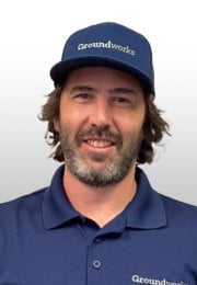 Man with a beard wearing a blue cap and polo shirt with "Groundworks" logo, smiling at the camera.